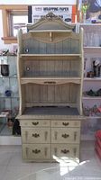 Front view of antiqued kitchen shelf showing 6 drawers and 4 open shelves with scalloped edges and distressed finish.