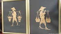 Two framed art pieces with bamboo leaf art of Asian figures carrying baskets on poles against a dark background.