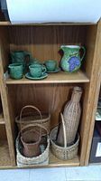 Photo showing green ceramic dishes and several wicker baskets on shelves.