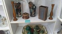 Two tall wooden candle holders, three large glass vases filled with potpourri, two pieces of brown pottery, and a rectangular tea tray with green pottery frog flower displays.