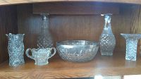 Full view of 6 cut glass items: bowl center, vases and decanters sides