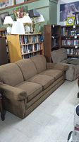 Brown Lazy Boy queen sleeper sofa with three seat cushions and padded armrests in a room with bookshelves and lamps in the background.