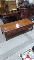 Photo showing entire rosewood coffee table from a side angle to display three drawers and top surface condition.
