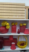 Shelf set with various red vases and yellow artificial flowers and decor basket.