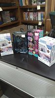 Four boxed items displayed: two Disney Frozen II twin sheet sets, one Alien vs. Predator action figure, and one LOL Surprise doll toy.