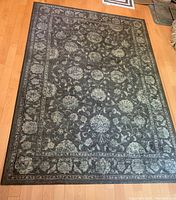 Full view of floral patterned carpet laid on wooden flooring showing detailed overall design and shape.
