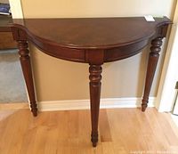 Front view of demilune table showing shape, leg details, and finish.