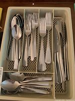 Tray with Oneida stainless steel flatware organized in compartments including spoons, forks, knives, and teaspoons.