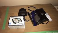Garmin Nuvi 2557 LMT GPS device in box, with cables and mount, and two binoculars with protective cases.