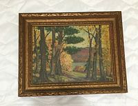 Front view of framed landscape painting showing autumn trees, a water body and distant hills under a light sky