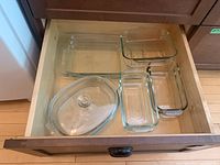 Overhead view of the open drawer containing all eight clear Pyrex glass dishes including loaf pans, casseroles, and the lidded casserole.