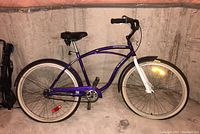 Full side view of the Raleigh adult tourist bicycle with purple frame and white front fork, showing tires, seat, and handlebars.