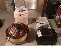 Photo showing all four appliances together: Breadman bread maker at the back, Canadian General Electric crock pot at front with lid and removable insert, Black & Decker hand mixer on bread maker, toaster on right.