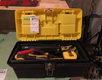 Stanley plastic toolbox open showing internal removable tray with assorted tools including pliers, a tape measure, screwdrivers, and a level.