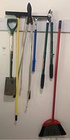 Full view of all hanging yard and cleaning tools including shovel, extension cord, pruning shears, broom, and squeegee.
