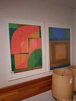 Two framed abstract geometric color block artworks displayed on wall
