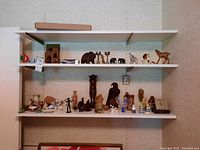 Wide shot of shelving with assorted figurines, carved animals, and ceramics.