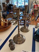 Front view of both three-arm candelabra and small shaker on tabletop