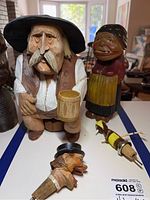 Photo showing all four wood carved items together on table including the man with mug, woman nutcracker, and two bottle stoppers