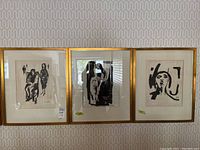 Three framed black-and-white abstract figurative watercolour paintings side by side on a patterned wall.