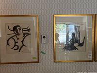 Both framed paintings hung side by side on patterned wallpaper