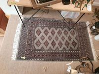 Top-down photo showing entire rug under a glass-topped desk, displaying pattern and size relative to desk.