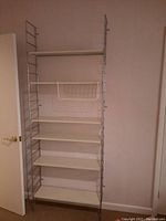 Full view of the metal frame shelving unit with six white shelves and silver metal side supports, showing its height and shelving arrangement.