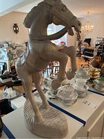 Side view of the carved wooden horse showing details in the head, neck, and front legs, including cracks on front leg.