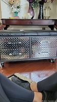 Front view of metal bench showing two of the four diamond plate drawers with metal handles and black cushioned seat above.
