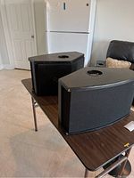 Two Bose 901 Series VI speakers on table with refrigerator and furniture in background