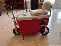 Front and side view of the red battery powered Cruisin Cooler scooter with insulated cooler body and handlebar