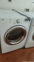 Front-left angle view of LG Tromm dryer showing control panel and door.