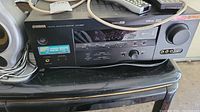 Front view of Yamaha AV receiver on black table with remote controls and cables on top.