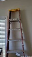 Full view of 8ft Werner fiberglass ladder leaning against wall, showing aluminum steps and yellow safety top.