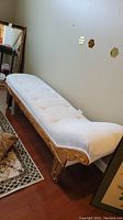 Full side view of the chaise lounge showing shape, upholstery, and wood frame.