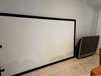 Photo showing a large white projection screen with black border next to the JVC CRT TV.