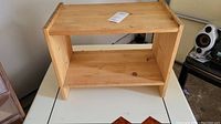 Wooden shelf in light natural wood color with open sides and two horizontal shelves.