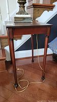 Wooden accent table with dark brown finish, rectangular top, and straight legs; cords seen on floor.