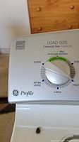 Close-up of control panel showing load size dial with auto-load sensing and multiple setting options on GE Profile washing machine.