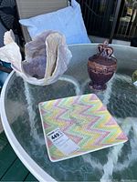 Glass table displaying the three ceramic decor items: faux shell, urn, and patterned plate.