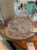 Photo showing cut glass bowl with serving spoon resting on an appetizer platter, all clear crystal with detailed cut designs.