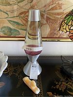 Lava lamp with silver base and purple lava visible, alongside the alabaster sphinx figure on a decorative surface.