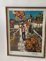 Framed signed and numbered print depicting man holding balloons outdoors near building.