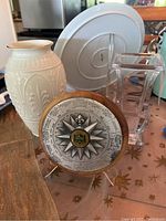Lot showing three items: cream Lenox vase with gold rim, clear glass vase, nautical plaque with compass design on wood stand.