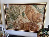 Frontal view of the framed silk painting showing two large butterflies in earthy tones with leaves and branches, framed in a gold slim frame with glass.