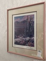 Framed art print displayed against a wall, showing the wood frame and beige matting.
