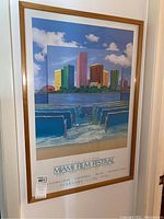 Photo of framed Miami Film Festival poster showing colorful buildings over ocean and theater seats.