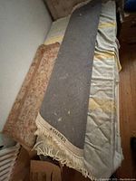 Photo showing the reverse side of the Persian-style carpet and the edge of another carpet, lying on a bed.