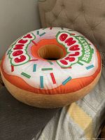 Large donut-shaped plush pillow with colorful sprinkles and 'Coney Island Brooklyn' text on white glaze surface.