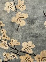 Close-up of carpet showing gray background with beige floral motifs and brown stems, highlighting the design and condition.